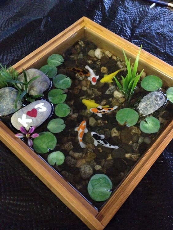 A square box water garden where the plants and ornament rocks are strategically placed at the sides to reserve the middle space for fish space. 
