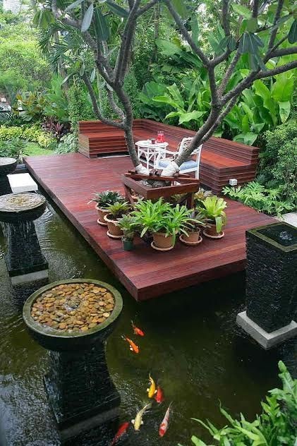 A maple-colored deck on top of a koi pond, decorated with four basin-like fountains.