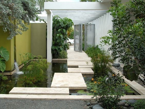 A mini courtyard filled with a koi pond with a flat stone-slab walkway on top.