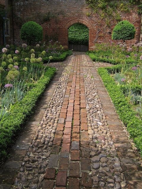 A rustic path design that uses a combination of bricks and multi-colored stones