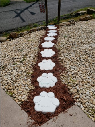 A personalized pathway made of molded concrete with the names of pets engraved on each slab. 