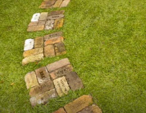 A garden pathway design with a personalized touch due to the engravings on the bricks.