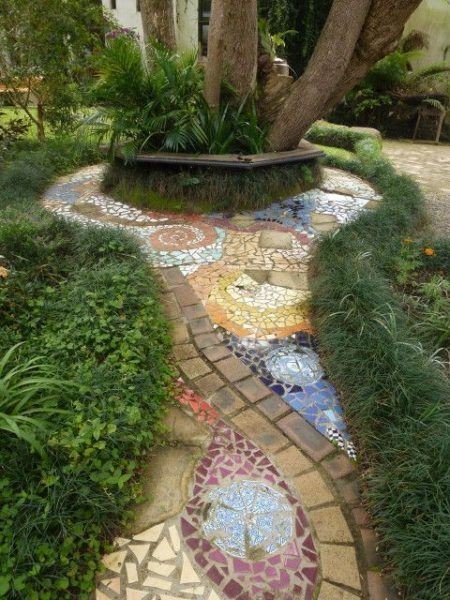 A light-colored garden pathway designed with different tile colors and a stretch of bricks.