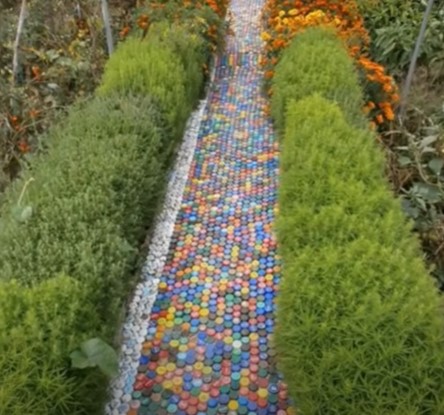 A garden path design that uses colorful small pentagon stones to create a young and vibrant vibe in the garden.