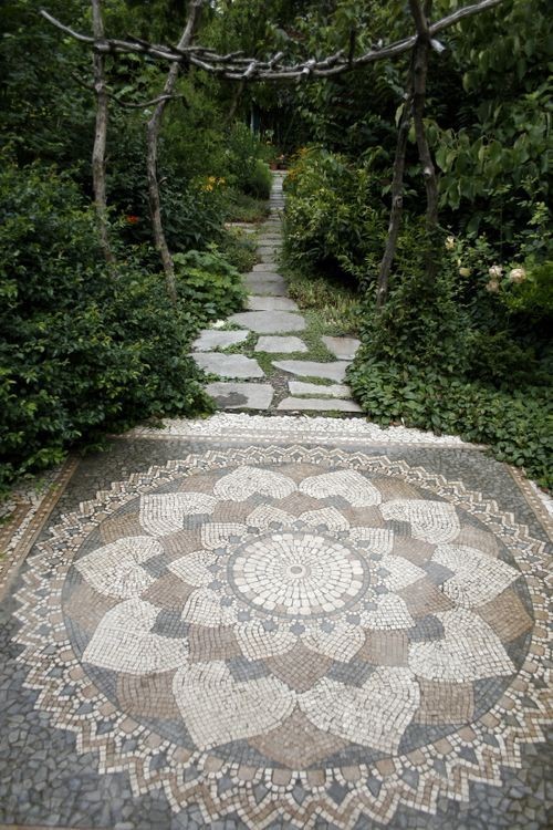 A garden path made of small colored tiles and bluestones.