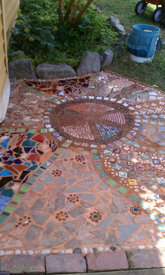 A mosaic garden path design mixing different hardscaping materials like bluestones, orange-colored cement, shite stones, and multi-colored stones. 