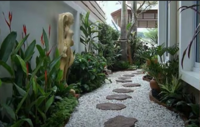 A garden pathway with wavy edges designed with roughly-rounded stone slabs and light-colored pea gravel.