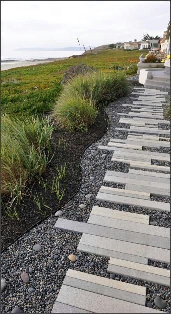 A garden pathway that uses thin-slate stones as stepping platforms on top of loose pea gravel.