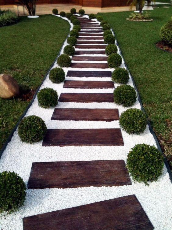 A garden path filled with white pebbles where the wooden planks serve as the stepping platform.